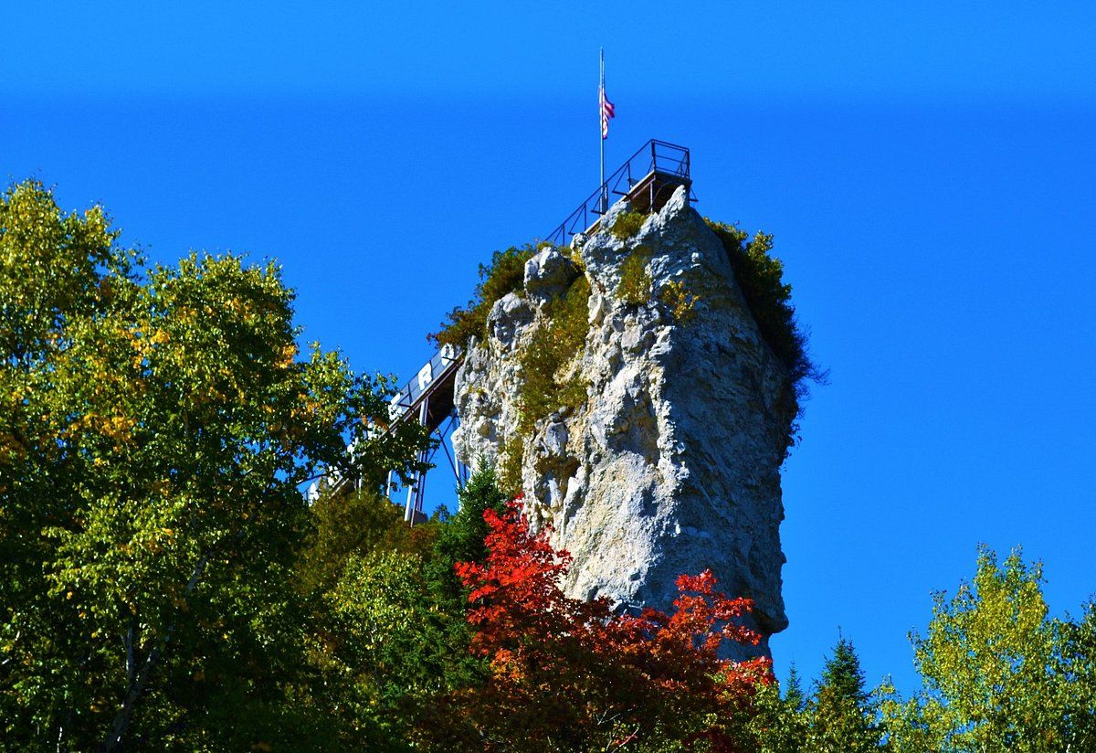Castle Rock, a limestone sea stack with a viewing platform and flag on top, framed by fall color