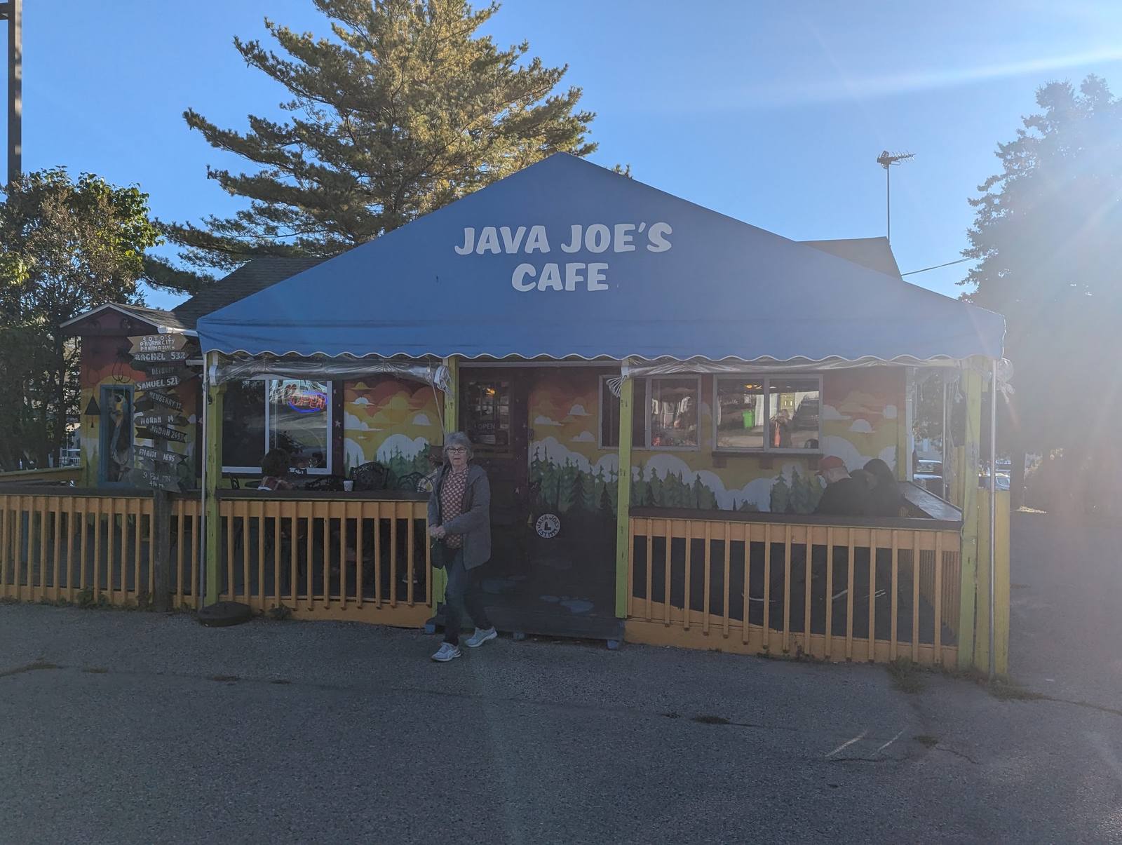 Java Joe's Café in morning light: blue awning, painted forest mural, and porch seating