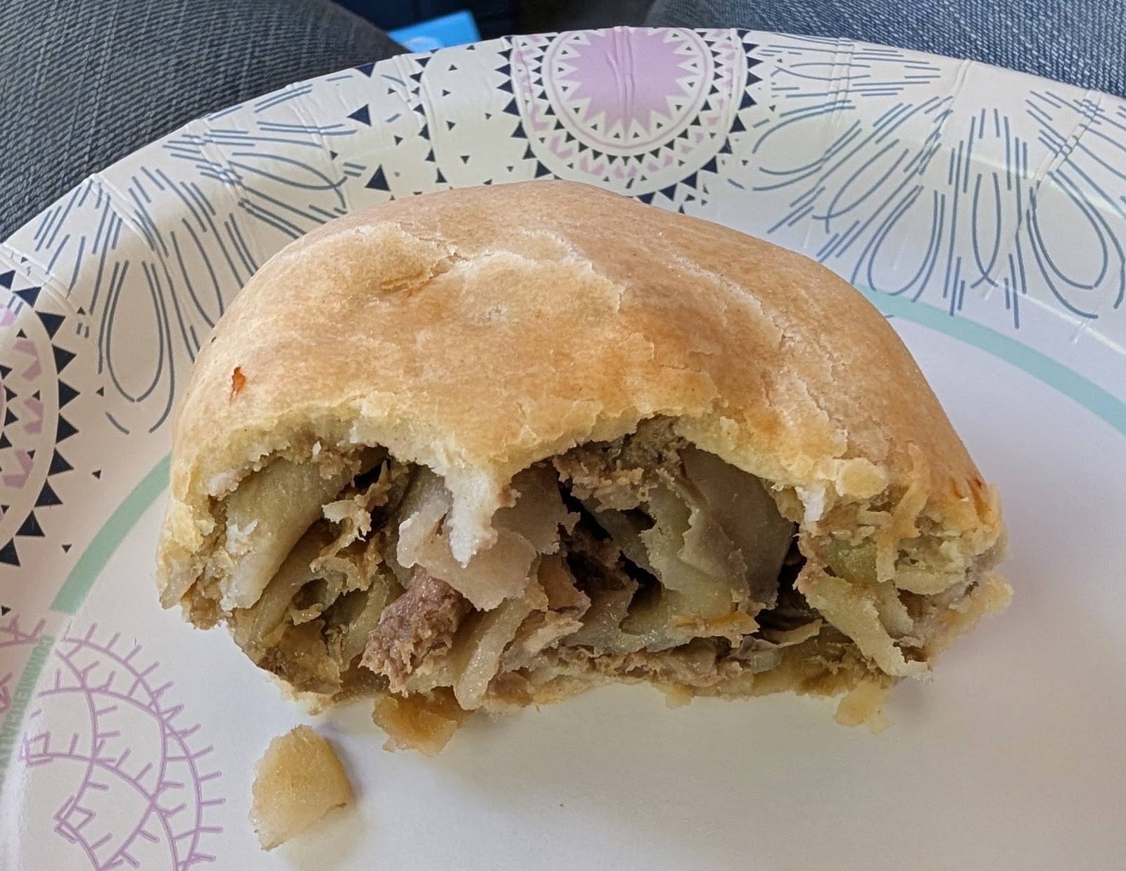 A Lehto's pasty broken open on a plate, showing the beef, potato, and rutabaga filling