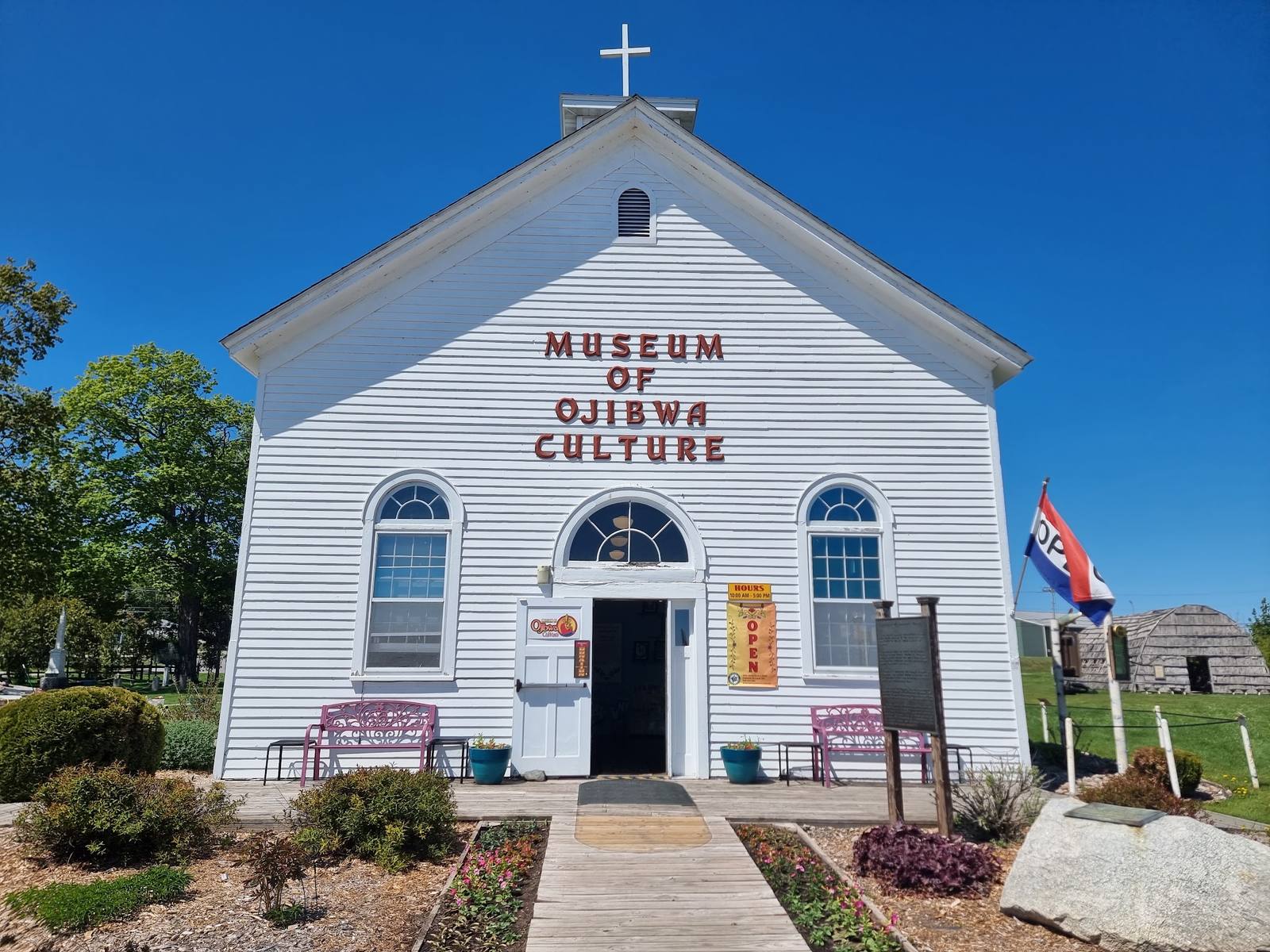 The Museum of Ojibwa Culture, a white former mission church, with the longhouse visible behind it